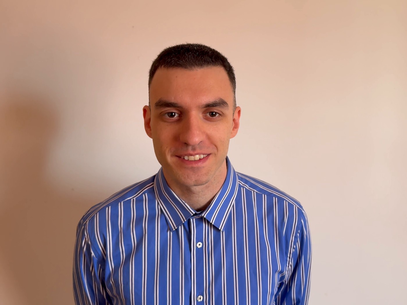 Vlad, the operator behind DVlad, smiling in a blue striped shirt
